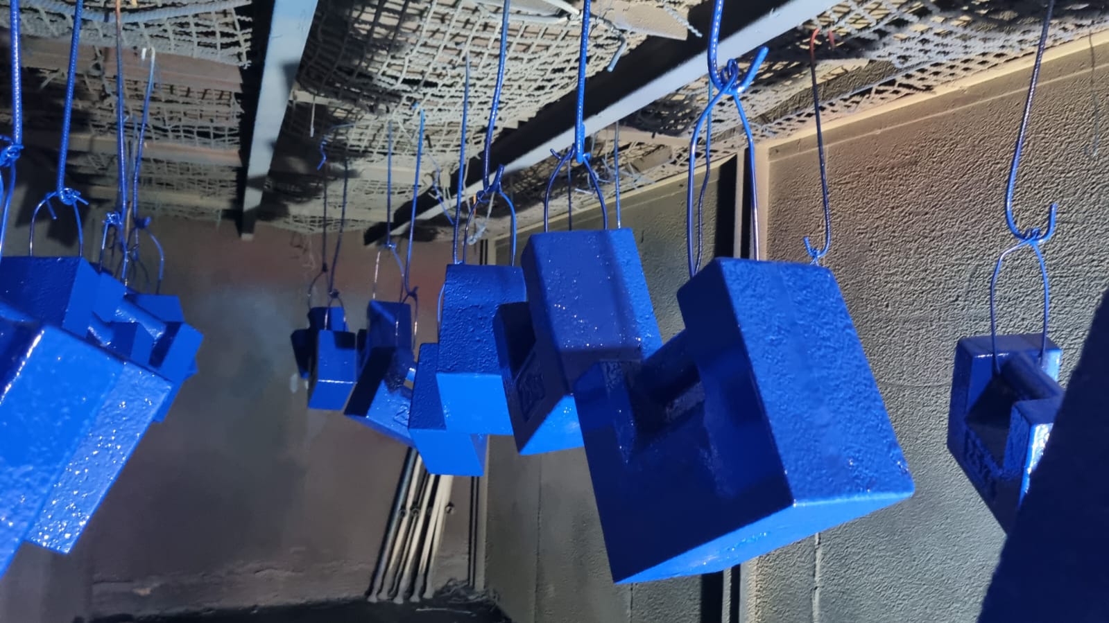 Piezas azules colgadas tras pintura electrostática